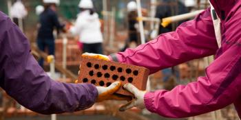 Volunteers pass a brick on a Habitat build site