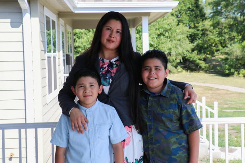 Claudia with her two young sons standing on their porch.